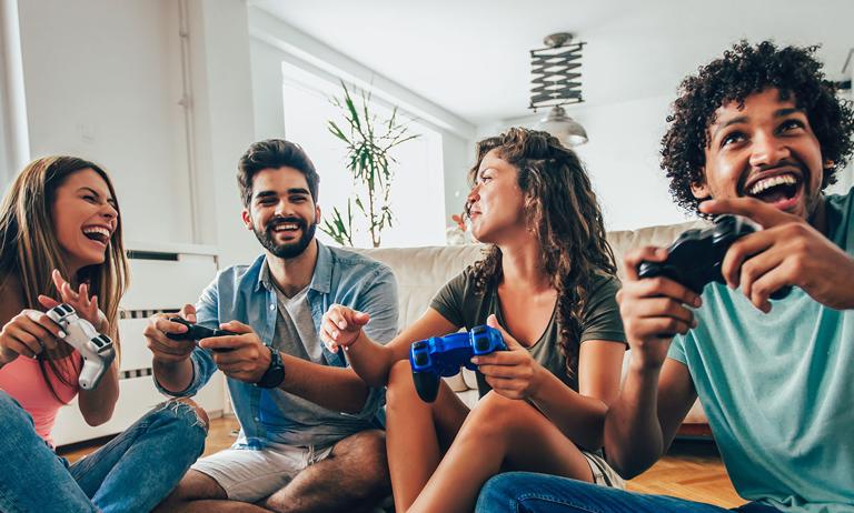 Photo of young adults sitting on floor playing video game